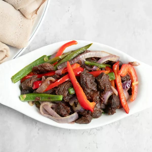 Ethiopian Tibs, a dish of sautéed beef, red bell peppers, green beans, and onions, with injera bread.